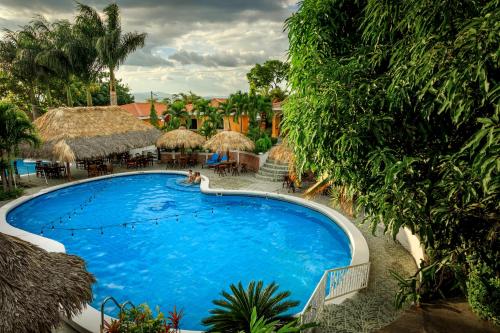 a large blue swimming pool next to a bunch of trees at Apart Hotel Acuarious de Luis in Estelí