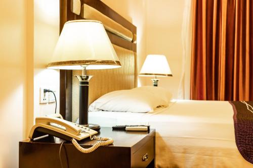 洛美Bravia Eco Hotel Lome的酒店客房配有电话和床。