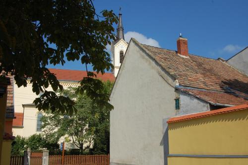 a white building with a church in the background at Belvárosi Rezidencia Pápa in Pápa