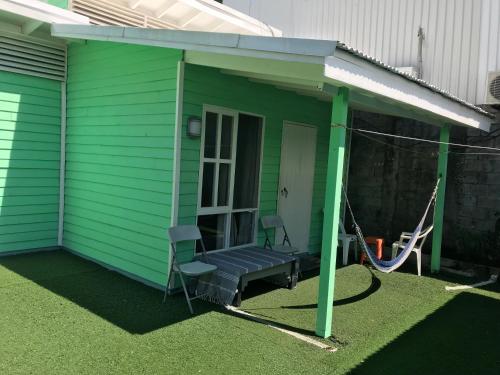 uma casa verde com um alpendre com um baloiço em green house two bedrooms em Sámara