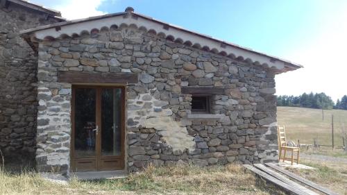 a stone building with a wooden door in a field at Nid de Poussins in Vaumeilh