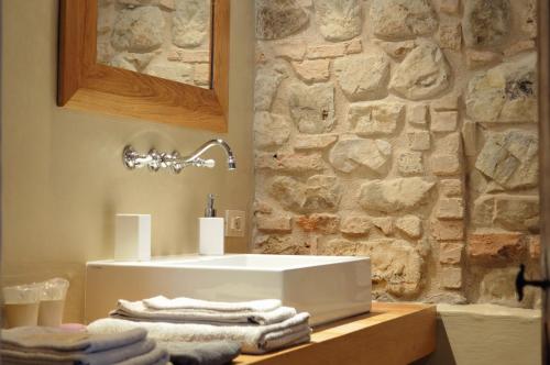 a bathroom with a white sink and a stone wall at Il Casale del Duca in Urbino
