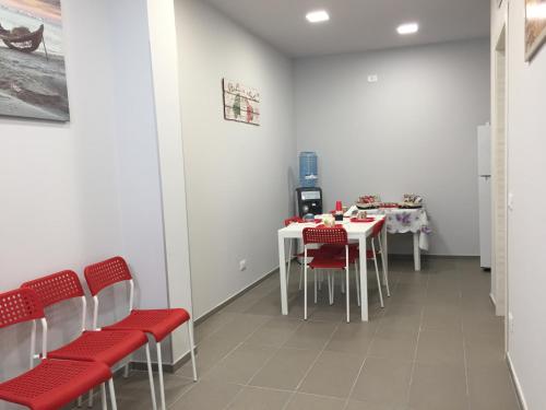 a waiting room with white tables and red chairs at B&B San Francesco di Paola in Vittoria