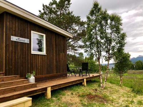a cabin with a wooden deck next to a tree at Morud in Meistervik