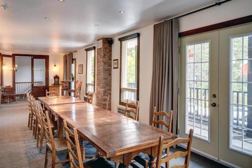 a large wooden table in a room with chairs and windows at Hotel Mont-Tremblant in Mont-Tremblant