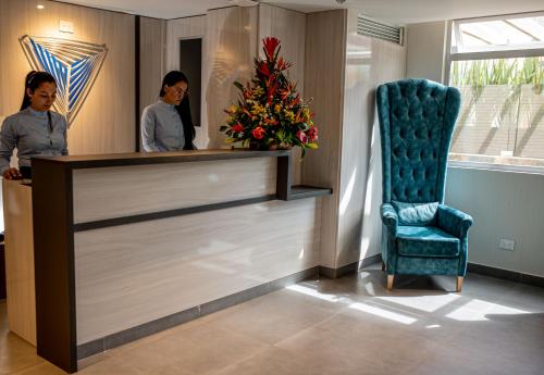 two women standing at a reception desk with a chair at Turrim Dei Hotel Boutique in Barbosa