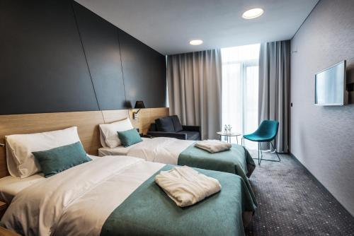 a hotel room with two beds and a chair at Regatta Hotel Restauracja Spa in Poznań