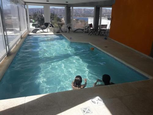 two children swimming in a large swimming pool at Refugio Playa Perelli in Villa Carlos Paz