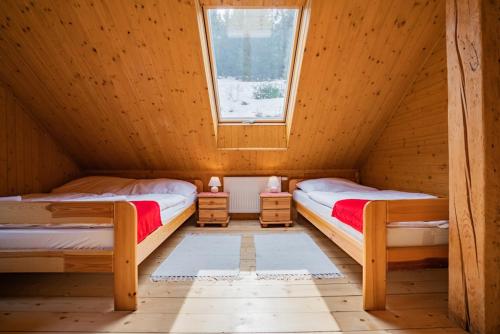two beds in a wooden room with a window at Chata Magurka in Partizánska ľupča