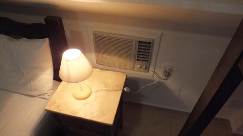 a bedroom with a bed with a lamp and a window at BH Studios Hotel Brás in Sao Paulo