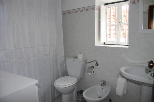 a white bathroom with a toilet and a sink at Casa São João in São Salvador da Aramenha
