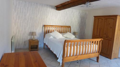 a bedroom with a wooden bed and a table at La Maison de Ners in Pertheville-Ners