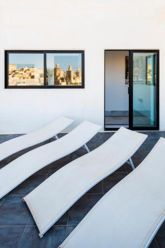 a row of white tables in a room with windows at Penthouse Retreat in Cospicua