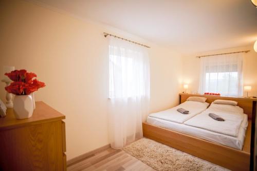 Eleven apartman house في كيزتيلي: غرفة نوم مع سرير و مزهرية مع الزهور الحمراء