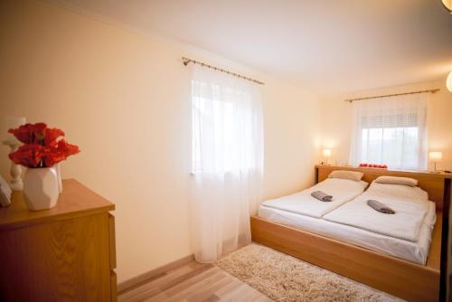 ケストヘイにあるEleven apartman houseのベッドルーム1室(ベッド1台付)、赤い花の花瓶1枚