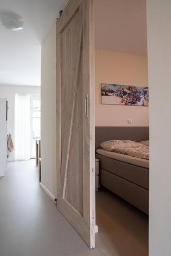 a sliding barn door in a bedroom with a bed at Santvort Luxury Apartment with Private Parking in Zandvoort