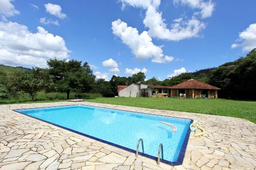 a swimming pool in a yard with a house at Pousada Soyndara in São Thomé das Letras