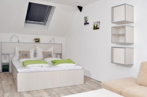a white bedroom with a white bed with green pillows at Gutshof Zum Adlernest in Arnsnesta