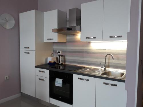 a kitchen with white cabinets and a sink at Station in Osijek