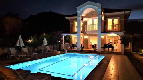 a swimming pool in front of a house at night at Dalyan Villa Amazon in Dalyan