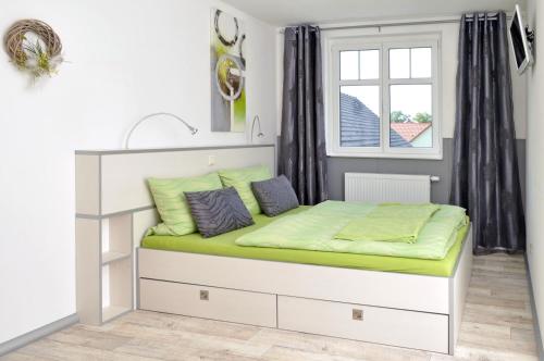 a bedroom with a white bed with green sheets at Gutshof Zum Adlernest in Arnsnesta