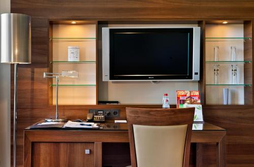 a kitchen with a television, refrigerator, and a coffee table at Flemings Selection Hotel Frankfurt-City in Frankfurt