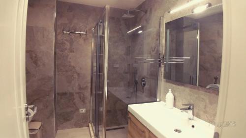 ein Bad mit einer Dusche, einem Waschbecken und einem Spiegel in der Unterkunft West Beach Apartment in Durrës