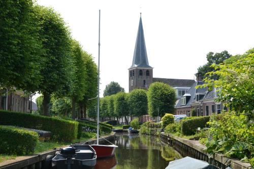 a church steeple and a river with boats in it at Stadsherberg 'Het Wapen van IJlst' in IJlst