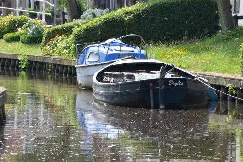two boats are docked on the water in a canal at Stadsherberg 'Het Wapen van IJlst' in IJlst