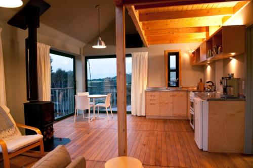 cocina y sala de estar con mesa y vistas en Hereweka Garden Retreat en Dunedin