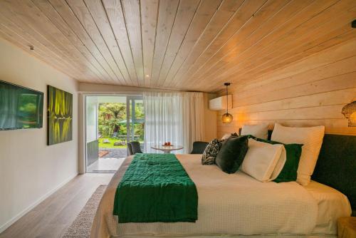a bedroom with a large bed with a wooden ceiling at Wairua Lodge - Rainforest River Retreat in Whitianga