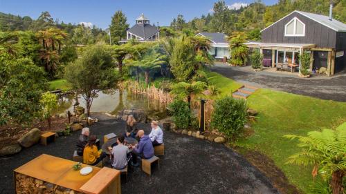 a group of people sitting at a table in a garden at Wairua Lodge - Rainforest River Retreat in Whitianga