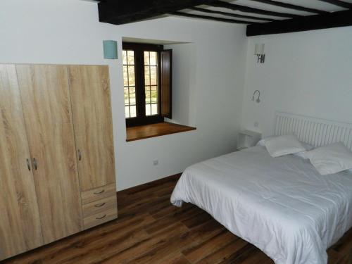 um quarto com uma cama branca e uma janela em Casona 1828 em Cabuerniga