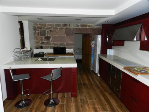 una cocina con armarios rojos y una barra con taburetes en Casona 1828, en Cabuérniga