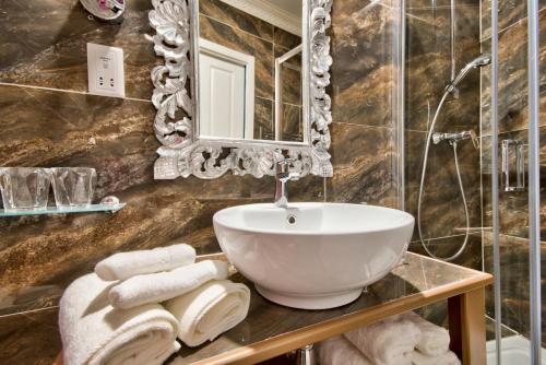 a bathroom with a sink and a mirror and towels at Julina Boutique Living in Mosta