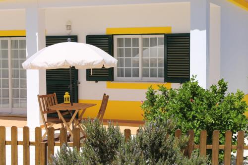 a table with an umbrella in front of a house at Casinha dos Avós in Lagos