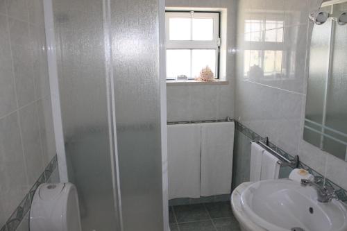 La salle de bains blanche est pourvue d'un lavabo et d'une douche. dans l'établissement Casinha dos Avós, à Lagos