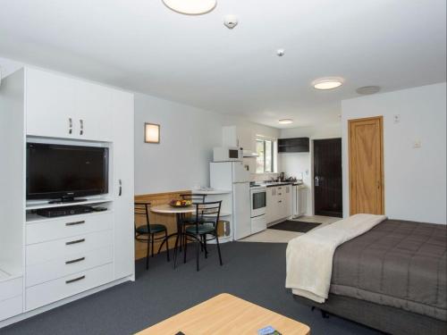 1 dormitorio con 1 cama y cocina con mesa en Clearbrook Motel & Serviced Apartments en Wanaka