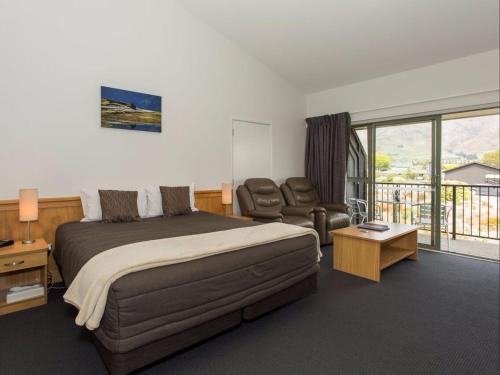 a bedroom with a bed and a couch and a chair at Clearbrook Motel & Serviced Apartments in Wanaka