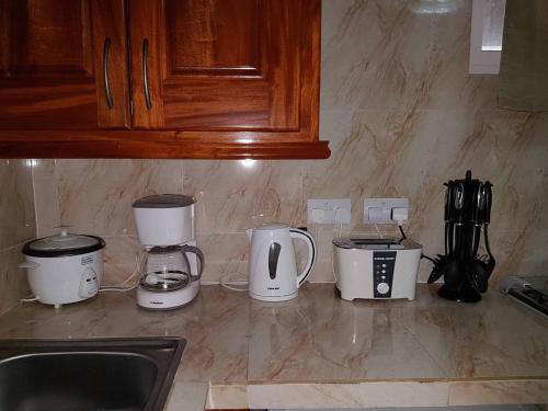 a kitchen counter with four coffeemakers and a sink at Mirella Villa Holiday Apartment in Anse Possession