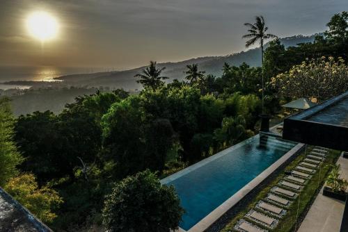 a house with a swimming pool and a view of the forest at The Puncak Lombok in Senggigi 