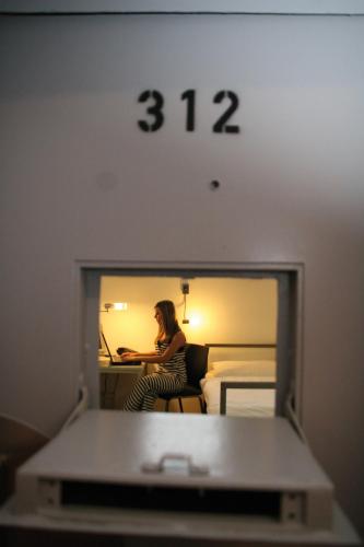 a woman sitting at a desk in a hotel room at ALCATRAZ Hotel am Japanischen Garten in Kaiserslautern