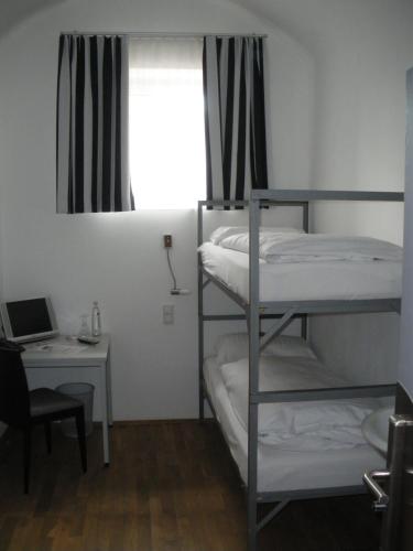 a room with bunk beds and a desk and a window at ALCATRAZ Hotel am Japanischen Garten in Kaiserslautern