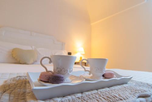 a tray with two cups and donuts on a bed at L'Altana City House in Brescia