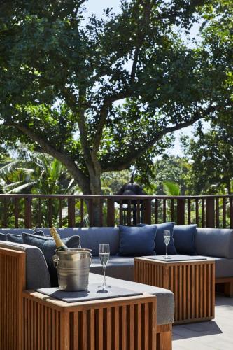 a patio with a couch and two tables with wine glasses at Hyatt Regency Bali in Sanur
