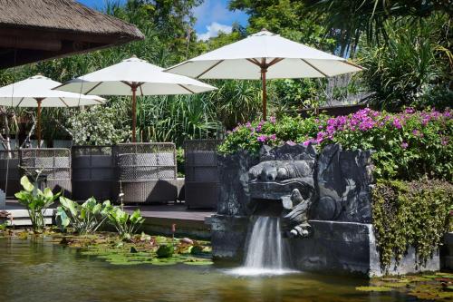 a fountain in a pond with flowers and umbrellas at Hyatt Regency Bali in Sanur