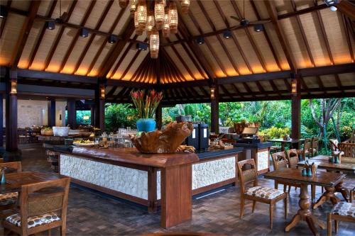 a restaurant with a bar with wooden tables and chairs at Hyatt Regency Bali in Sanur