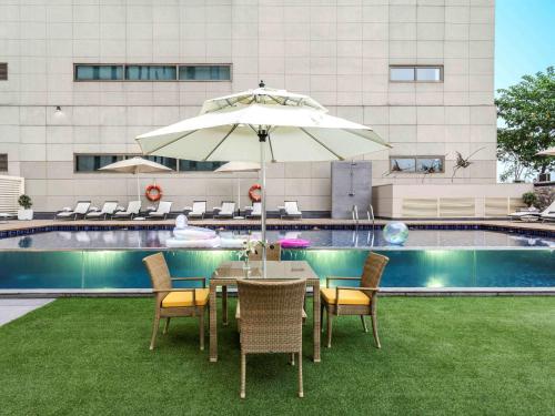 a table and chairs with an umbrella next to a pool at ibis New Delhi Aerocity - An Accor Brand in New Delhi