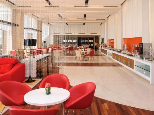 a restaurant with red chairs and tables and a cafeteria at ibis New Delhi Aerocity - An Accor Brand in New Delhi