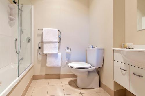 La salle de bains blanche est pourvue d'une douche et de toilettes. dans l'établissement Beachside Resort Motel Whitianga, à Whitianga